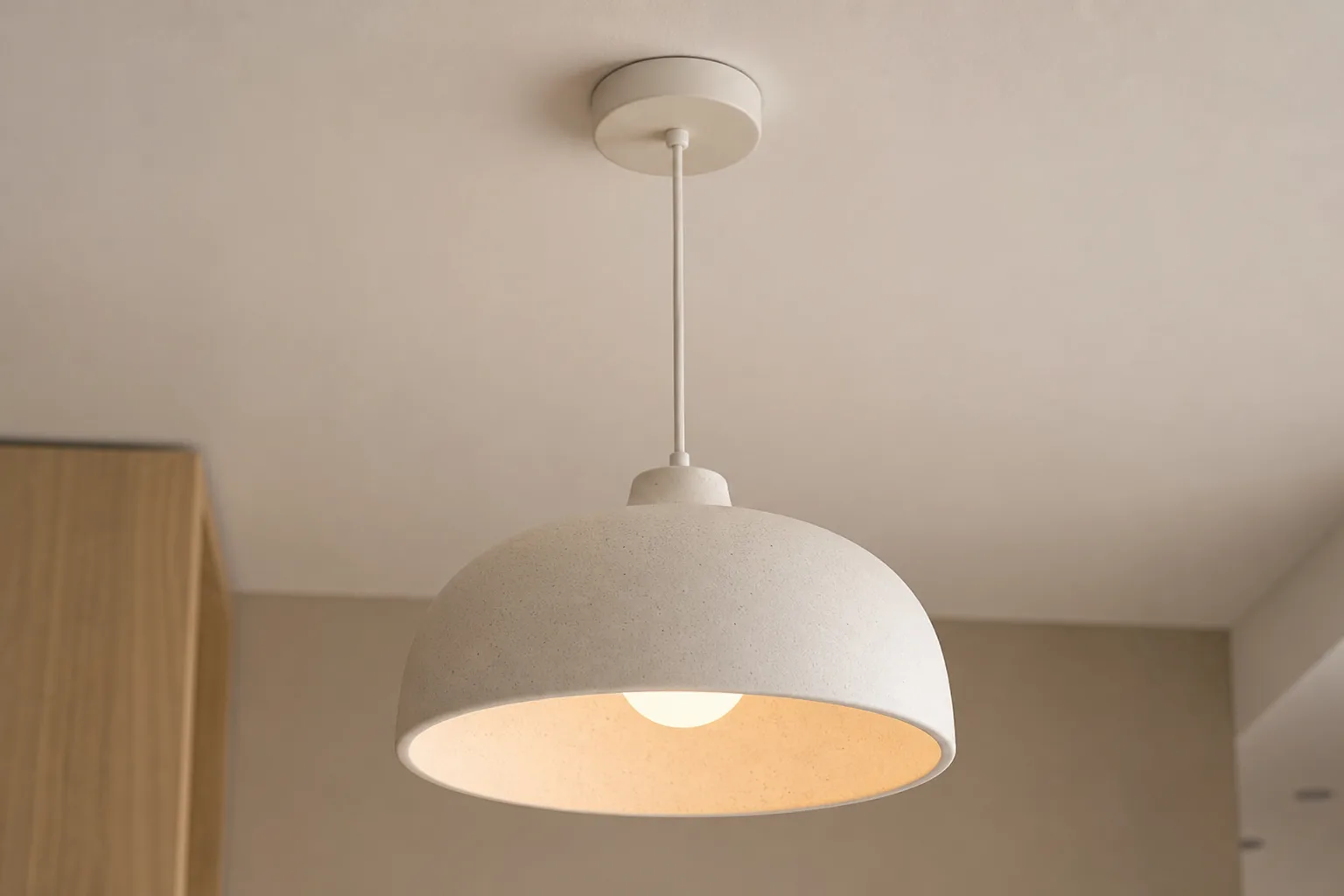 Suspension en céramique avec son câble et sa rosace fixée au plafond, ampoule placée dans l'abat-jour.