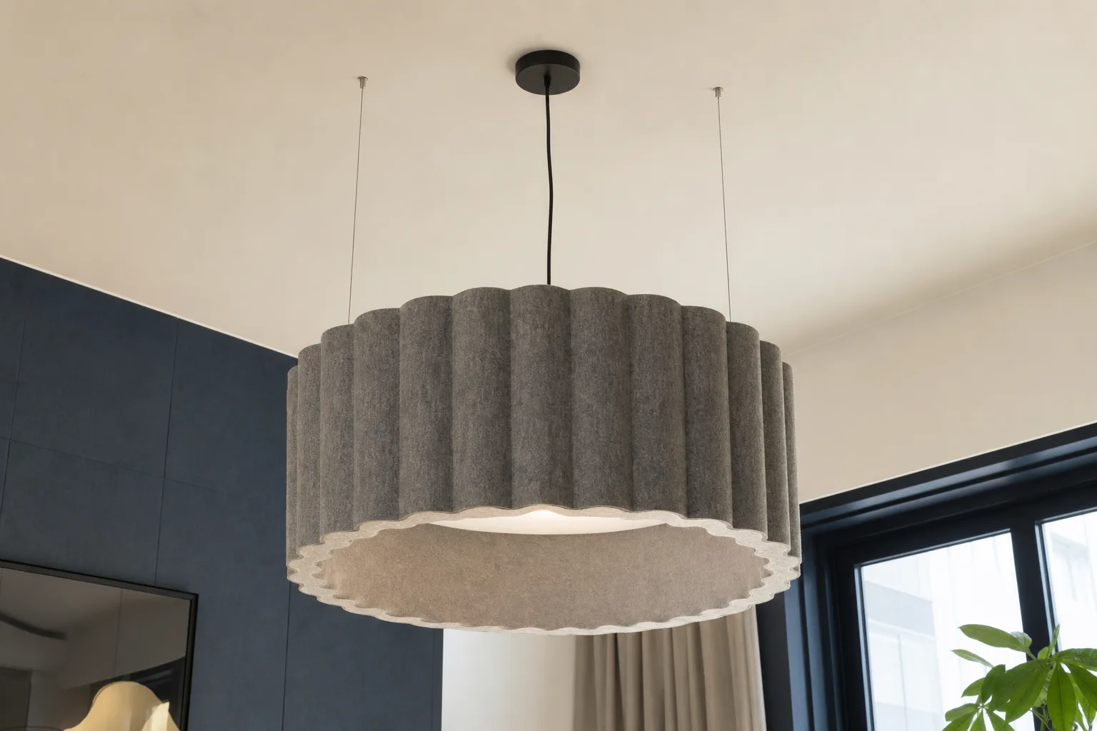 Rosace et câble d’une grande suspension acoustique fixée au plafond d’une pièce aménagée.