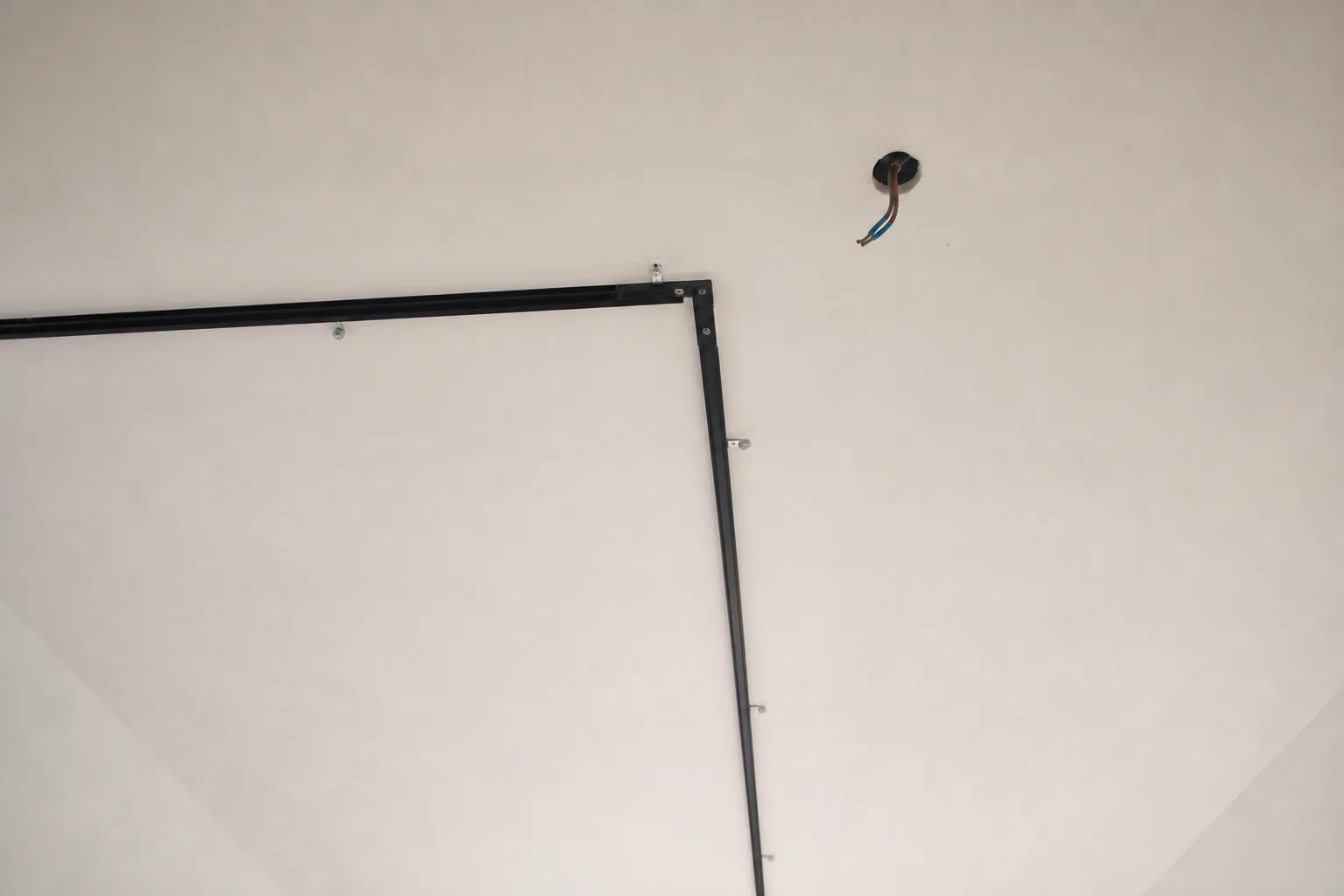 Une arrivée électrique au plafond se trouve à proximité d’un rail présenté à blanc avant sa fixation.