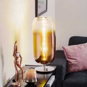 Lampe à poser Artemide Gople en verre cuivré et argenté sur un meuble