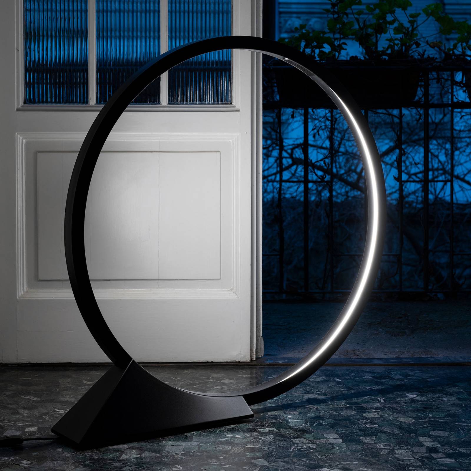 Lampadaire LED Artemide O noir à anneau lumineux diffusant une lumière blanche chaude