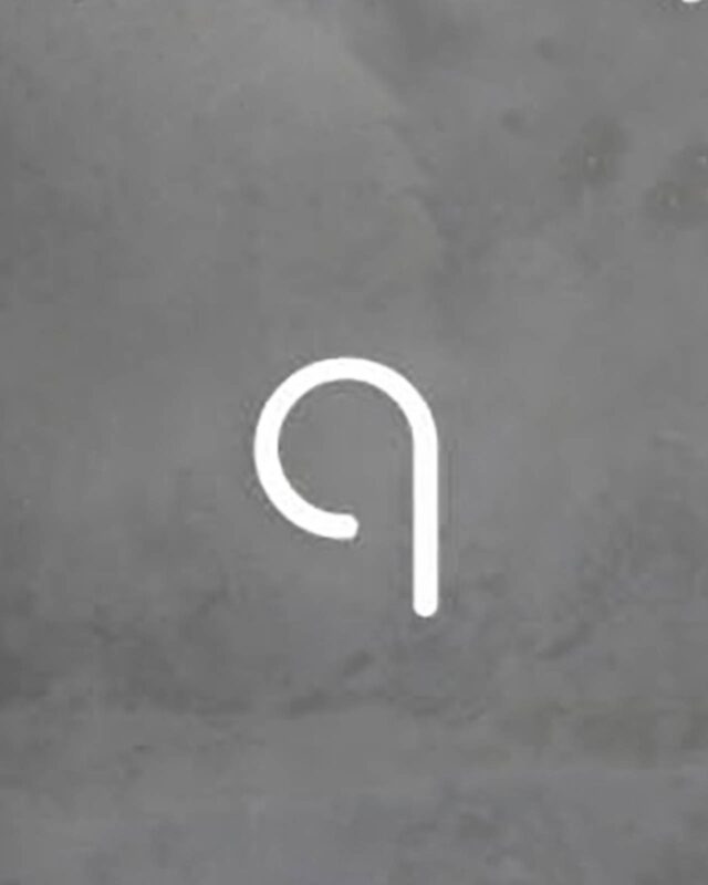 Applique Artemide Alphabet of Light q compose une signature lumineuse graphique sur le mur.